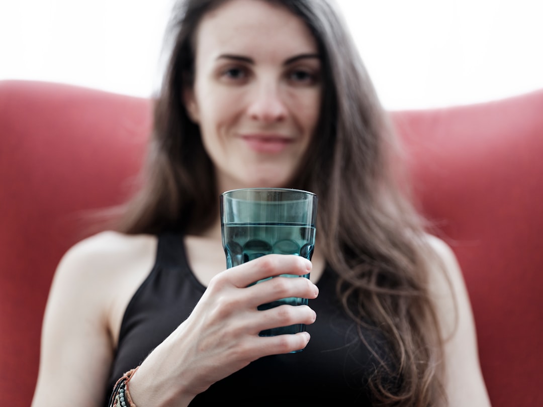 a woman holding a glass of water in her hand