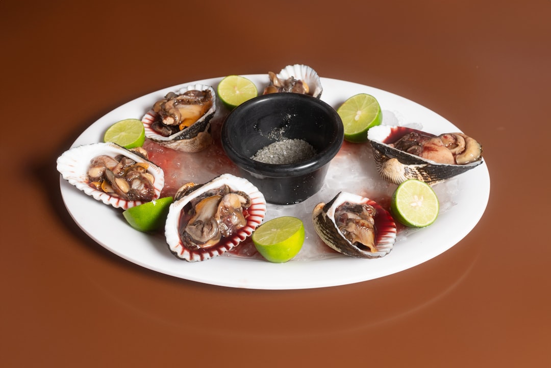 A white plate topped with oysters and lime wedges