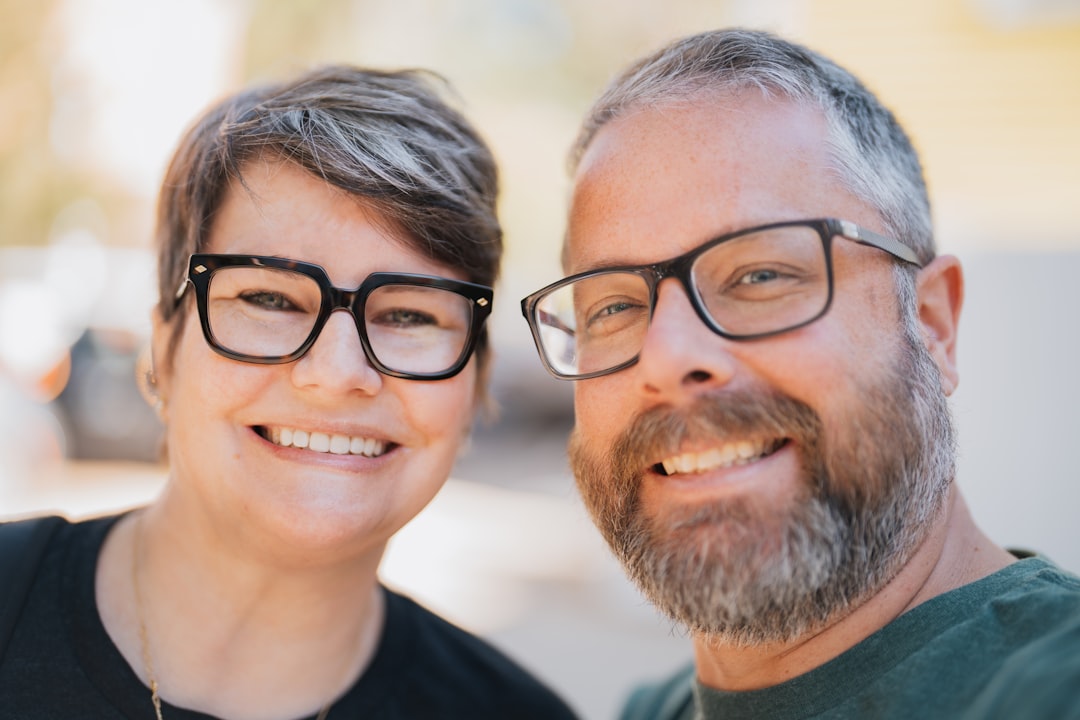 A smiling couple wearing glasses outdoors