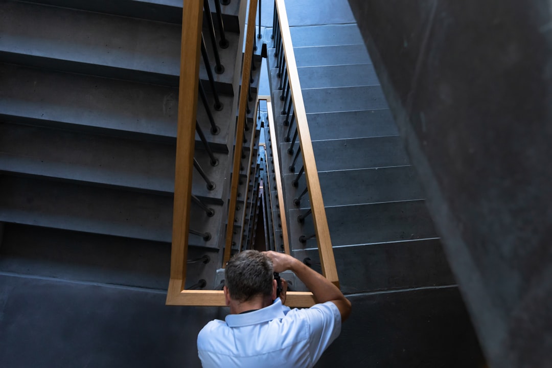 man wearing gray polo shirt standing beside rail