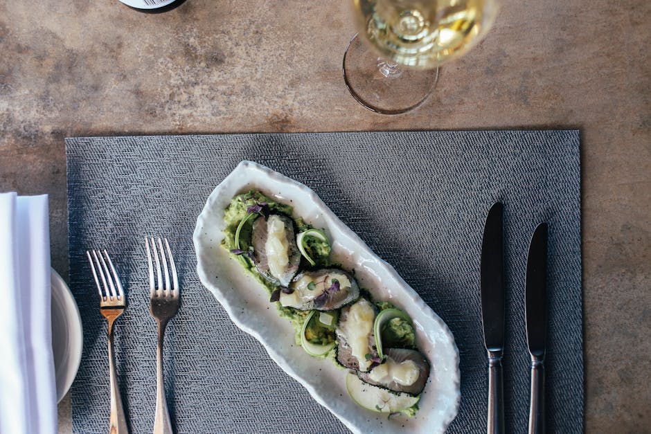 Top view of a gourmet seafood platter elegantly arranged with wine and cutlery.