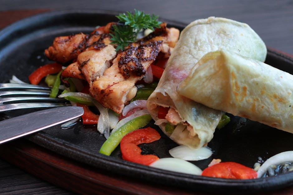 Delicious grilled chicken with peppers and onion wrapped in soft flatbread on a sizzling plate.