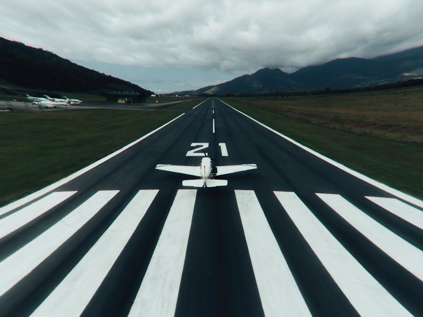 A small airplane on a runway ready for takeoff with scenic mountains in the background.