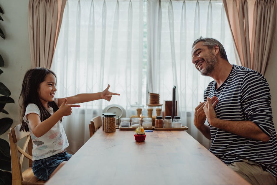Father and daughter share a joyful moment at the table with a cupcake and candle.
