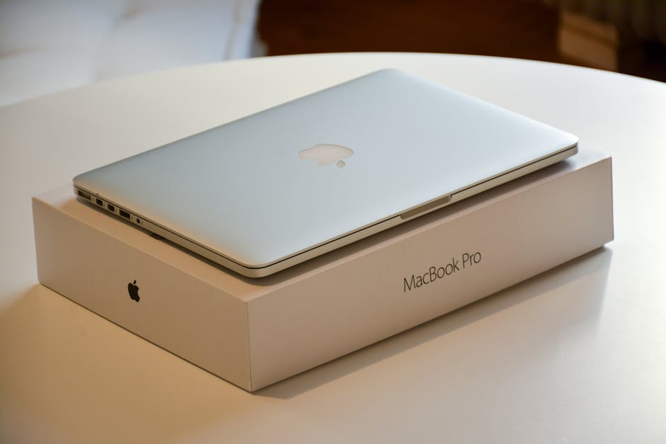 A MacBook Pro laptop placed on its original packaging on a white indoor table.