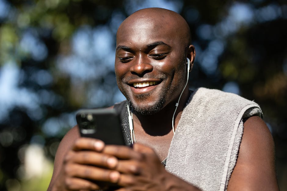 Happy man enjoying music with earphones and smartphone in a sunny outdoor setting.
