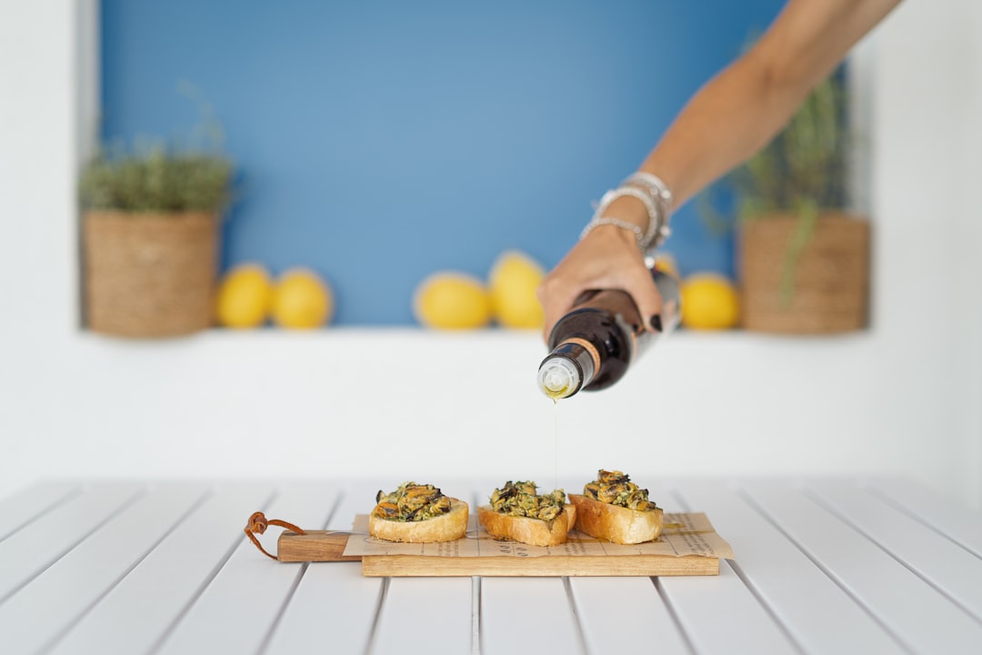 A person pouring a bottle of wine over a tray of food