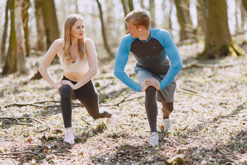 A couple engages in outdoor stretching exercises in a sunlit forest setting, promoting wellness and fitness.