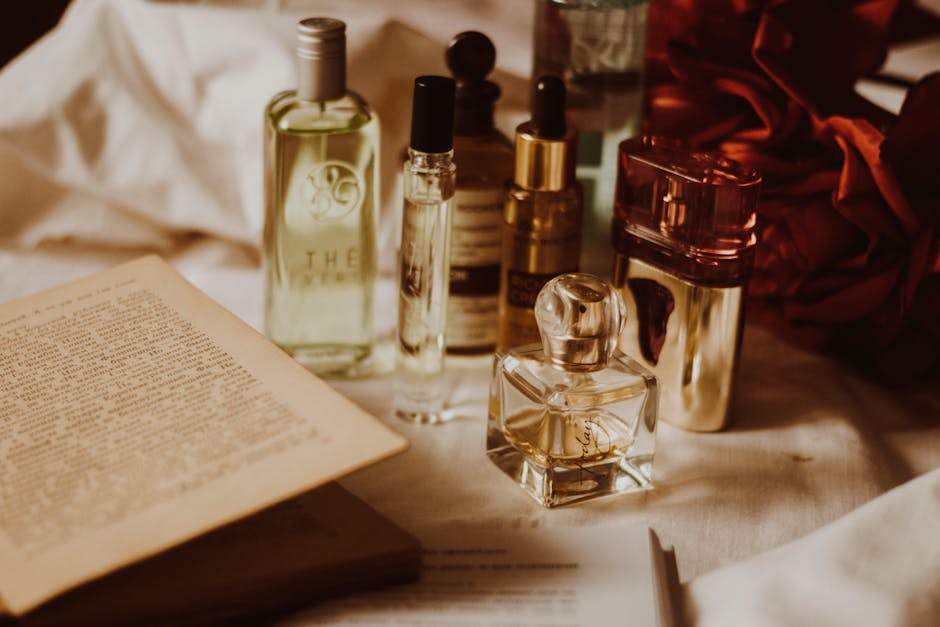 Aesthetic still life of assorted perfume bottles and an open book on a table.