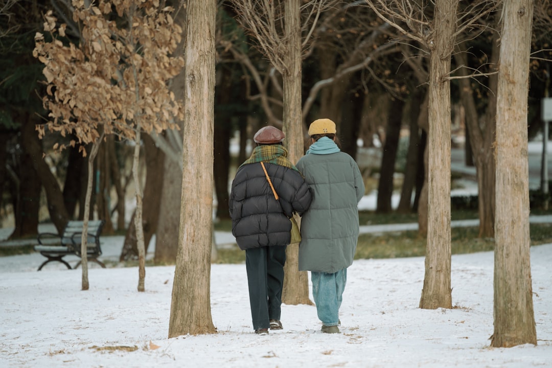 Two people walking arm in arm in a snowy park.