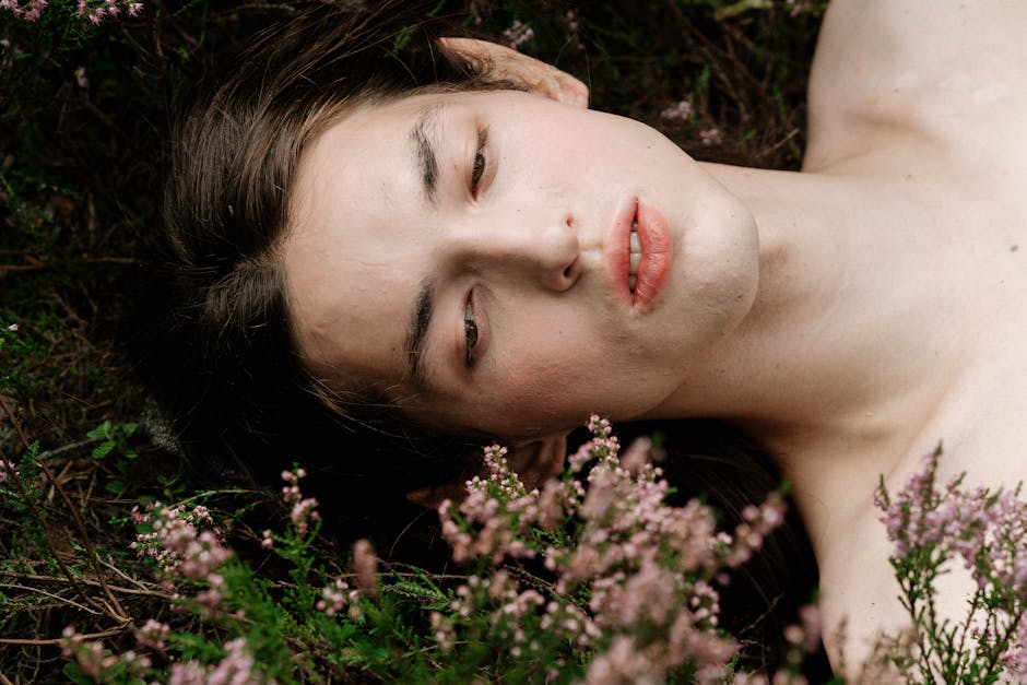 Serene close-up portrait of person lying among wildflowers outdoors.