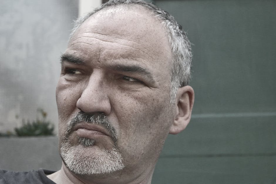 Close-up portrait of a thoughtful mature man with grey hair outdoors.