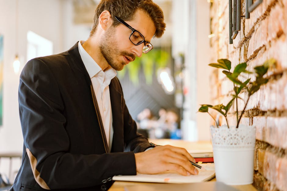 Focused businessman writing notes in a modern cafe setting with a stylish interior.